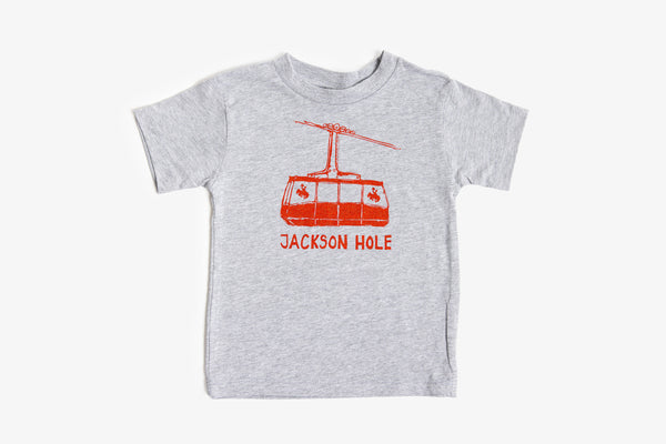 A toddler's heather gray short-sleeve t-shirt featuring a red cable car graphic and the text 'JACKSON HOLE' printed on the front, displayed against a clean white background.