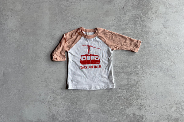 Children's t-shirt with a cable car graphic and 'Jackson Hole' text on a gray surface