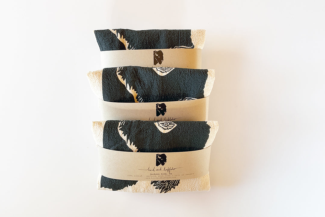 Three folded towels with black and white patterns on a white background