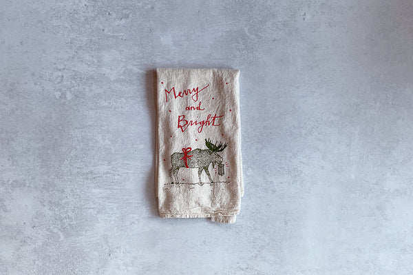 Decorative towel with reindeer and 'Merry and Bright' text on a gray background