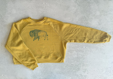 Yellow sweatshirt with a graphic design on a gray surface
