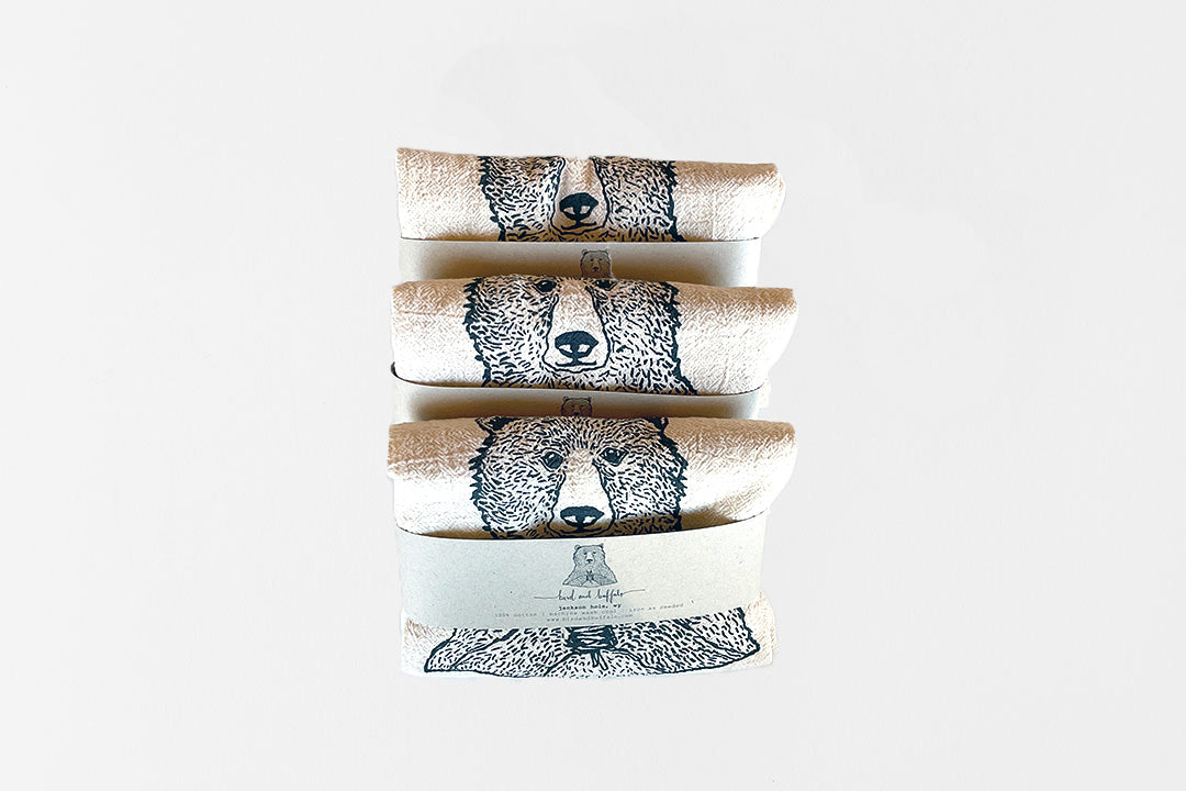 Three folded towels with bear designs stacked on a white background