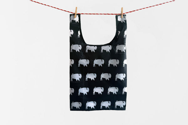 Black reusable shopping bag with white animal pattern hanging on a clothesline.